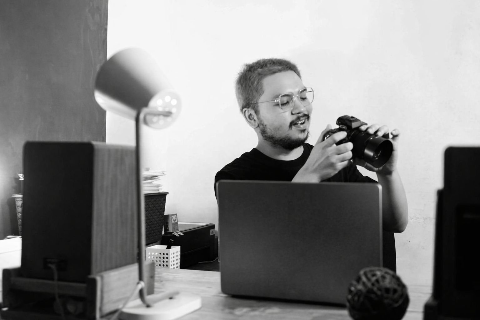 Man med kamera vid laptop i arbetsmiljö, symboliserar flexibelt arbete.