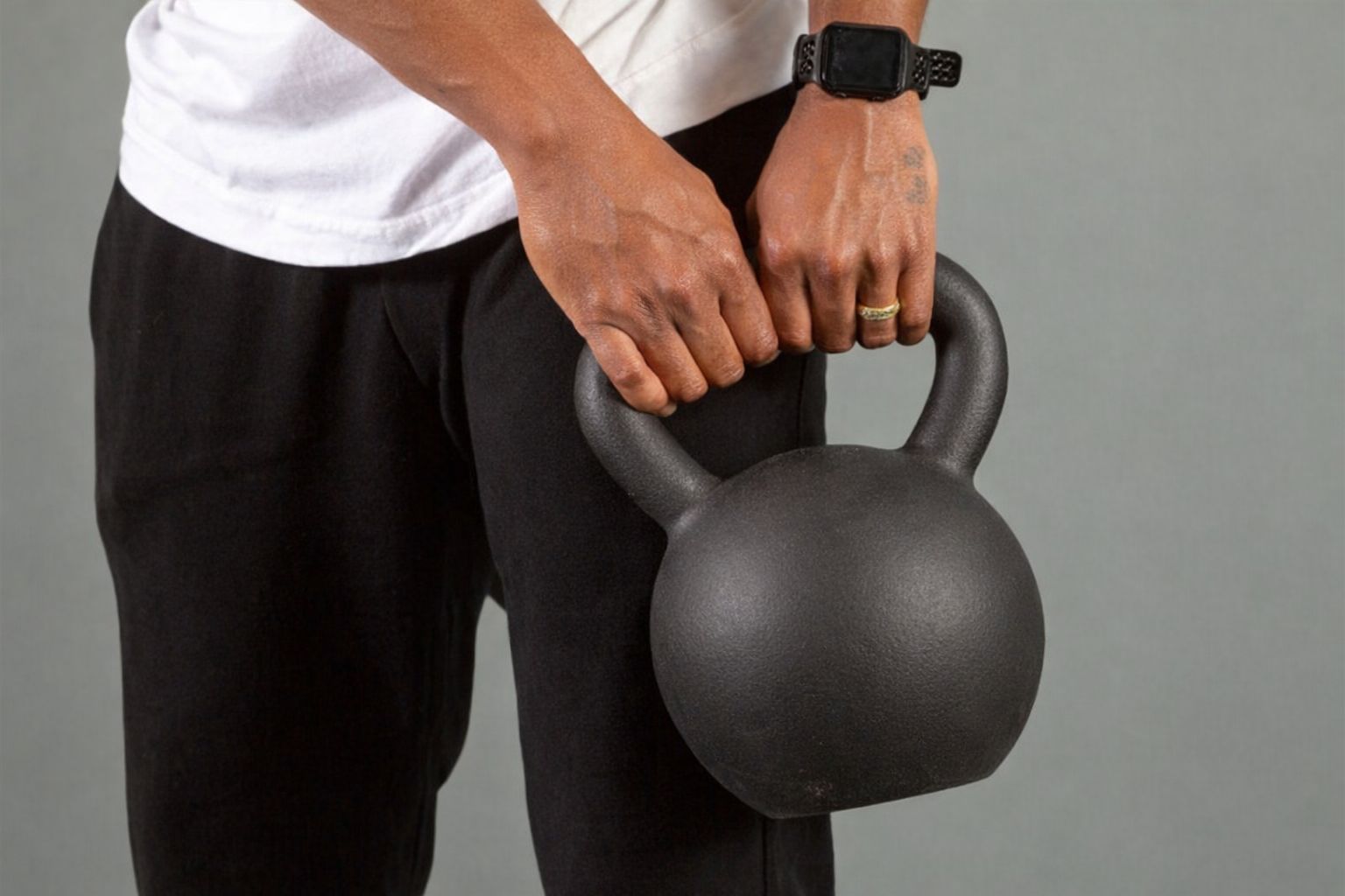 Närbild på person som lyfter en kettlebell i ett hemmagym.